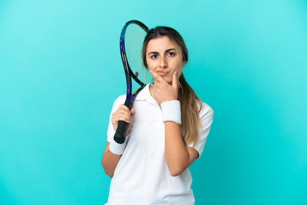 Młoda kobieta tenisistka na białym tle na niebieskim tle myślenia