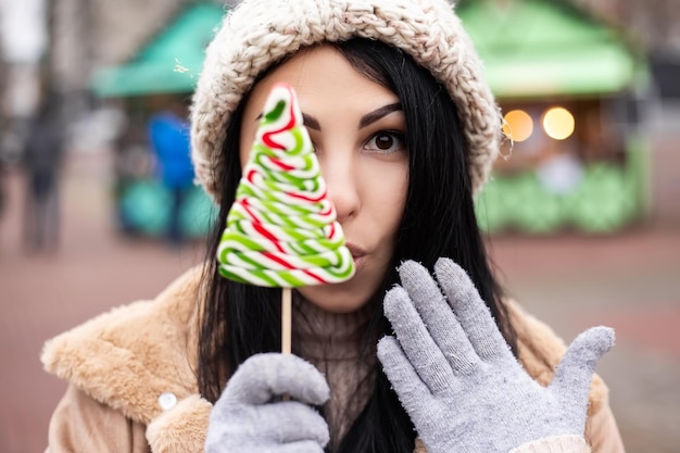 Zdjęcie młoda kobieta trzyma cukierki, stojąc na zimowych targach wakacyjnych