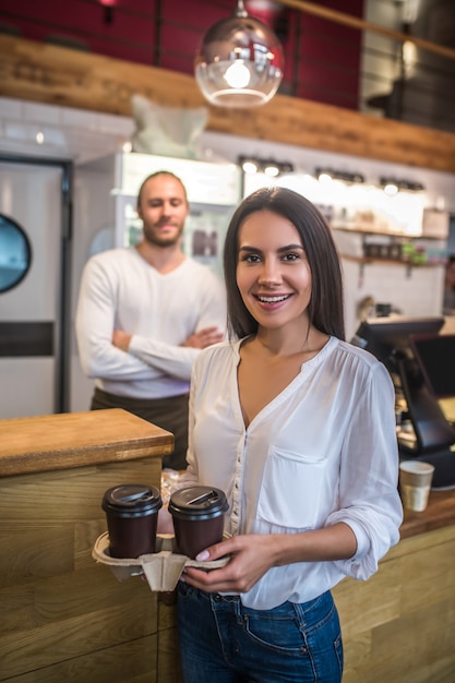 Młoda kobieta trzyma filiżanki kawy w kawiarni