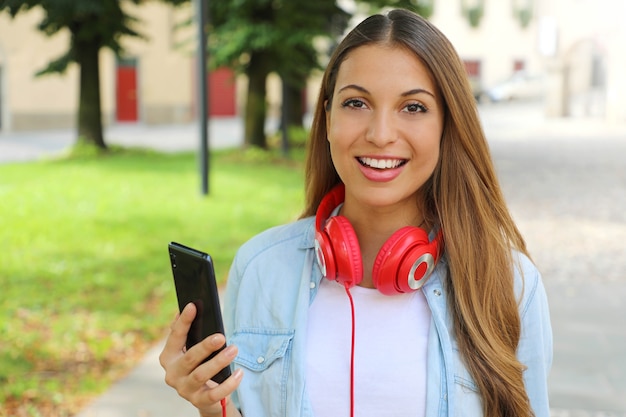 Młoda kobieta trzyma inteligentny telefon dla wybiera muzykę z jej nowej aplikacji mobilnej