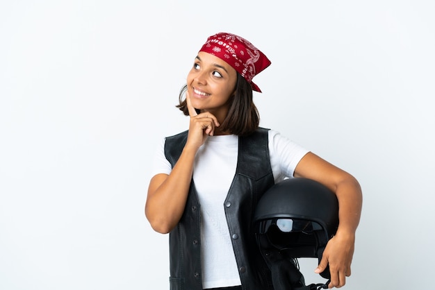Młoda kobieta trzyma kask motocyklowy na białym tle myśli pomysł, patrząc w górę
