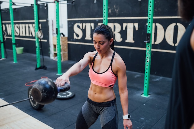 Młoda kobieta trzyma kettlebell salowego gym trening