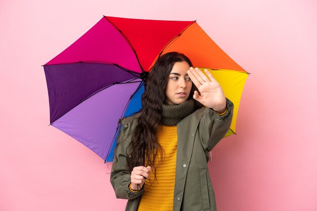 Młoda kobieta trzyma parasol na białym tle