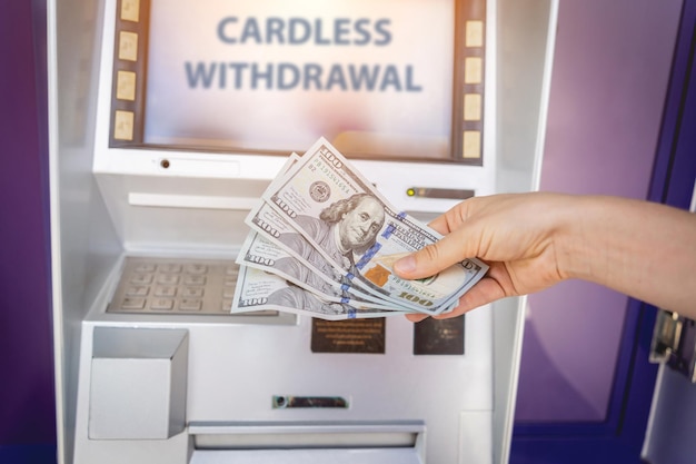 Młoda kobieta trzyma pieniądze w rękach po wypłacie gotówki w bankomacie
