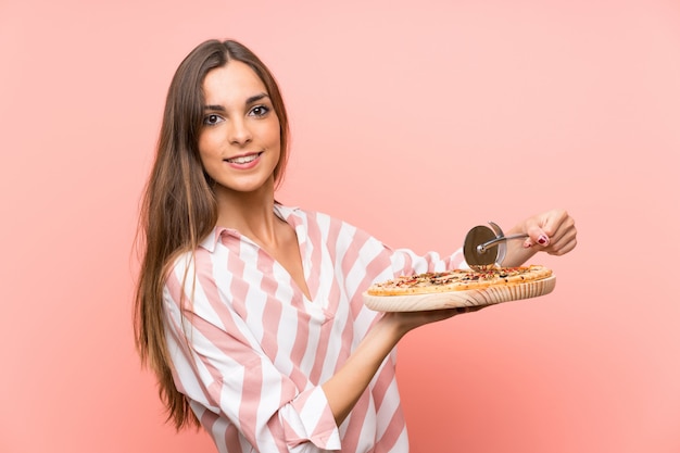Młoda kobieta trzyma pizzę nad odosobnioną menchii ścianą