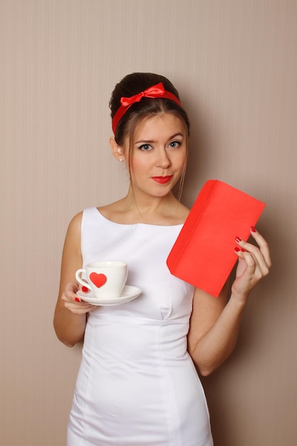 Zdjęcie młoda kobieta trzyma pocztę i kubek z czerwonym sercem
