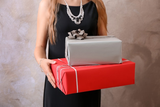 Młoda kobieta trzyma pudełka na prezenty na kolorowej powierzchni