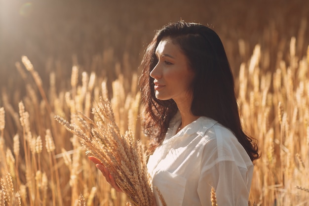 Młoda kobieta trzyma snop pszenicy kłosy w dziedzinie rolnictwa