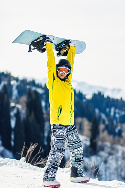Zdjęcie młoda kobieta trzyma snowboard nad głową na tle gór