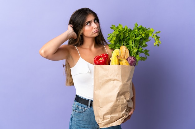 Młoda kobieta trzyma torbę na zakupy spożywcze, mając wątpliwości
