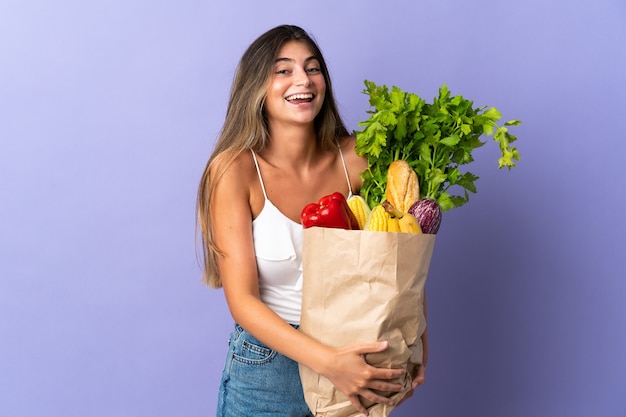 Młoda kobieta trzyma torbę na zakupy spożywcze, uśmiechając się dużo