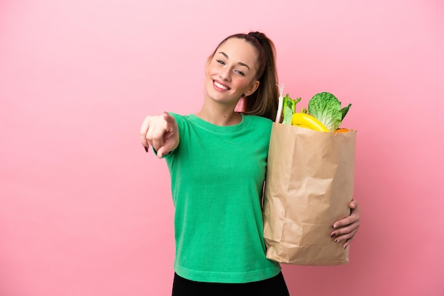 Młoda kobieta trzyma torbę na zakupy, wskazując przód z happy wypowiedzi