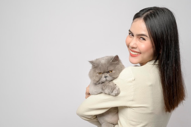 Młoda kobieta trzyma uroczego kota bawiącego się z kotem w studio na białym tle