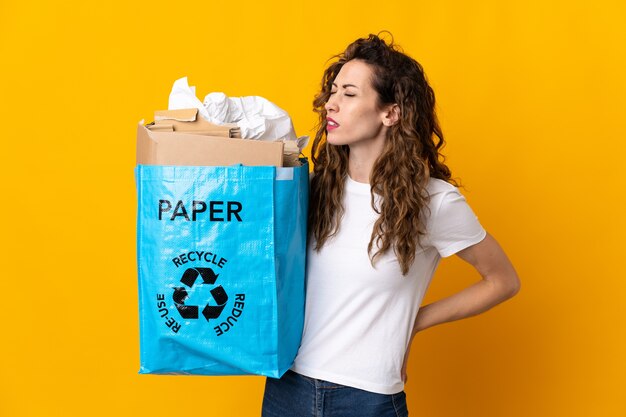 Młoda kobieta trzyma worek recyklingu pełnego papieru do recyklingu