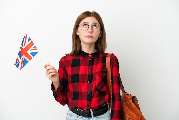 Młoda kobieta trzymająca flagę Wielkiej Brytanii na białym tle na niebieskim tle i patrząca w górę