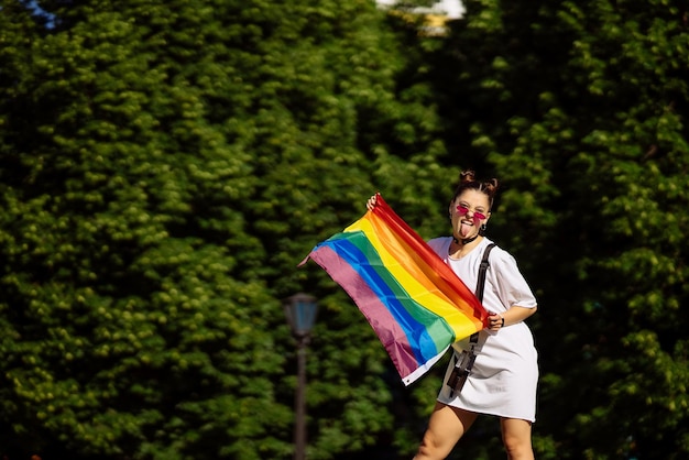 Młoda kobieta trzymająca w rękach flagę dumy LGBT