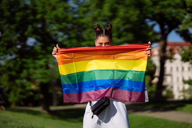 Młoda kobieta trzymająca w rękach flagę dumy LGBT