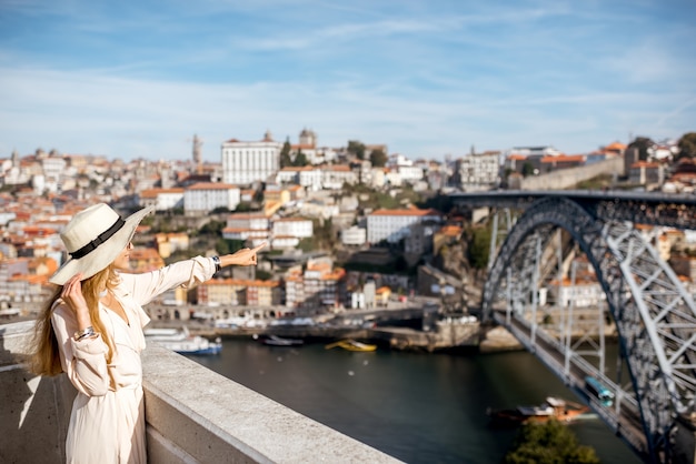 Młoda kobieta turysta cieszący się pięknym tłem pejzażu miejskiego ze słynnym mostem w mieście Porto, Portugalia