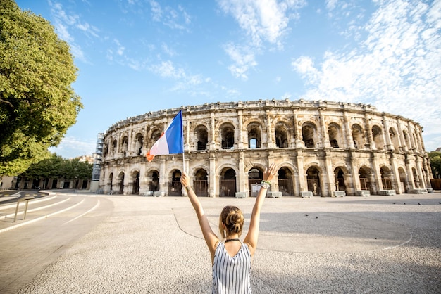 Młoda Kobieta Turysta Stojący Z Francuską Flagą Przed Starożytnym Amfiteatrem Na Starym Mieście W Nimes W Słoneczny Poranek We Francji.