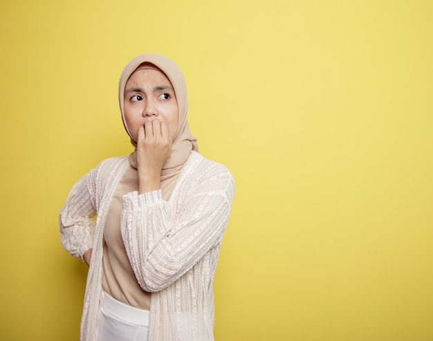 Młoda kobieta ubrana w hidżab z wystraszonym wyrazem na białym tle na żółtym tle