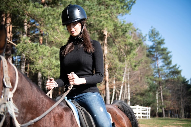 Zdjęcie młoda kobieta ubrana w kask i jadąca na koniu