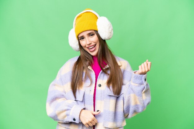 Młoda kobieta ubrana w zimowe mufki na odizolowanym tle kluczowania kolorem, wykonująca gest gitary