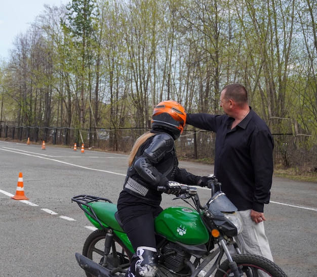 Młoda kobieta uczy się jeździć na motocyklu w szkole motocyklowej.