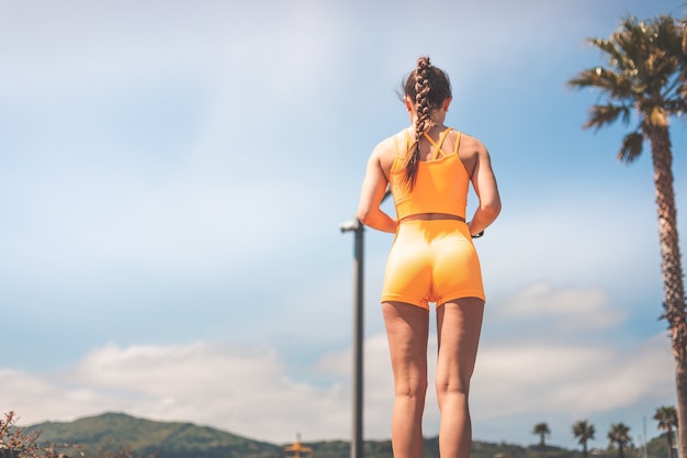 Młoda kobieta uprawiania sportu na sobie pomarańczowy zestaw sportowy w parku Hendaia, Kraj Basków.