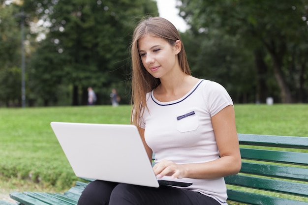 Młoda kobieta używa jej laptop outdoors