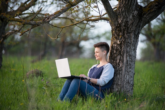 Młoda kobieta używa laptop outdoors