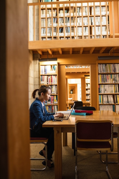 Młoda kobieta używa laptop w bibliotece