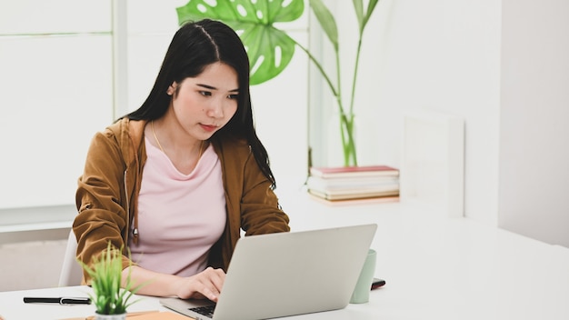 Młoda kobieta używa laptop w nowożytnym biurze