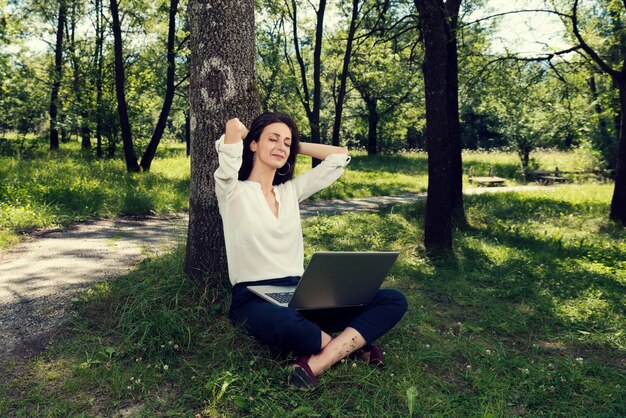 Zdjęcie młoda kobieta używająca laptopa na lądzie w lesie