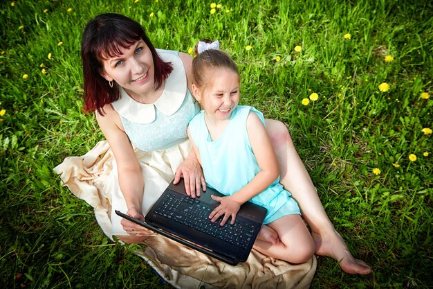 Zdjęcie młoda kobieta używająca laptopa siedząc na boisku