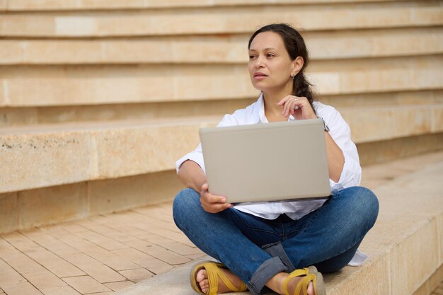 Zdjęcie młoda kobieta używająca laptopa, siedząc na schodach