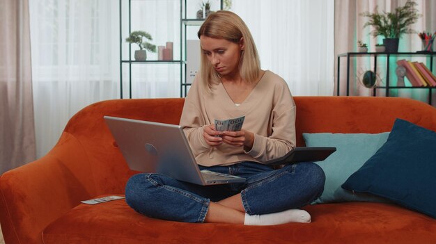 Zdjęcie młoda kobieta używająca laptopa siedząc w domu na kanapie