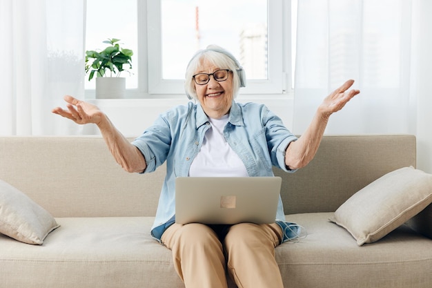 Młoda kobieta używająca laptopa siedząc w domu na kanapie