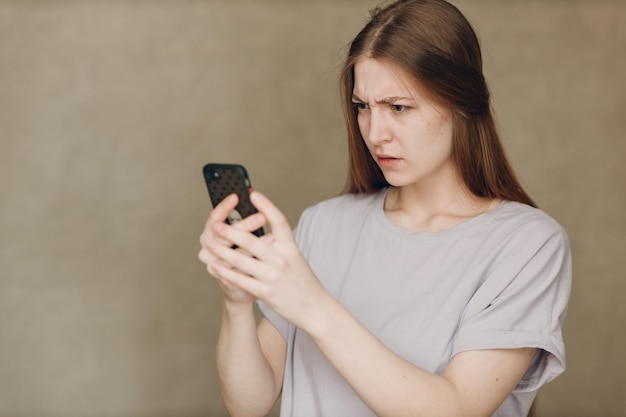 Młoda kobieta używająca telefonu komórkowego na brązowym tle