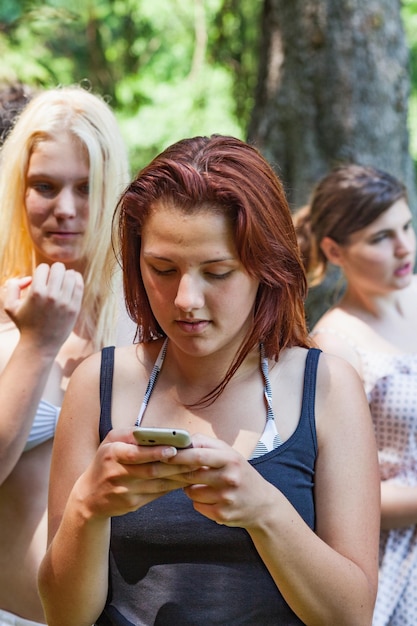 Zdjęcie młoda kobieta używająca telefonu komórkowego przeciwko przyjaciołom