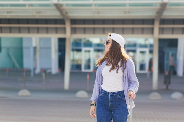 Młoda kobieta w białej czapce z walizką