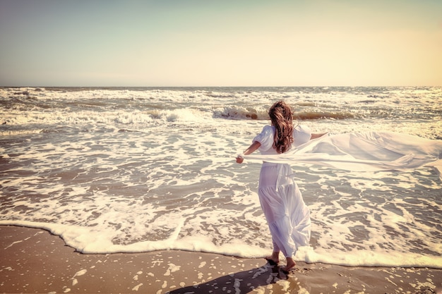 Młoda kobieta w białej sukience z pareo na plaży