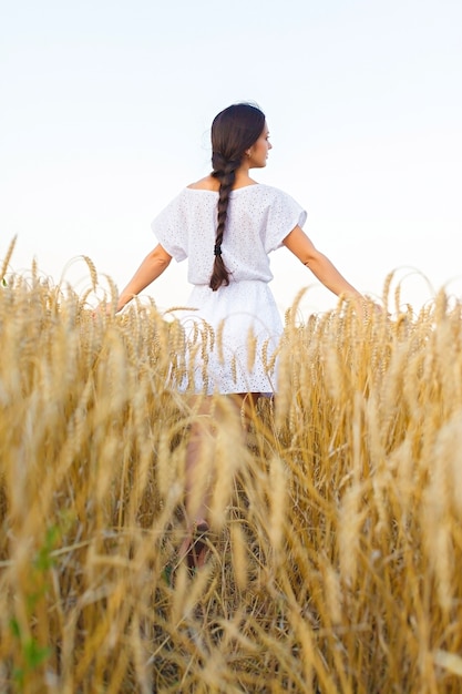 Młoda kobieta w białej sukni w polu pszenicy. dziewczyna w polu pszenicy