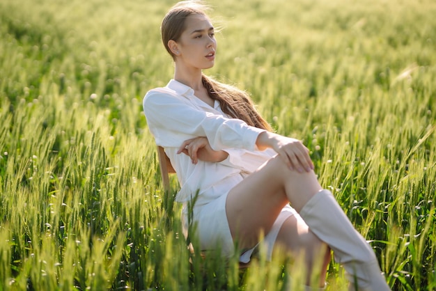 Młoda kobieta w białym garniturze stwarzających w zielonym polu pszenicy Koncepcja mody i stylu życia