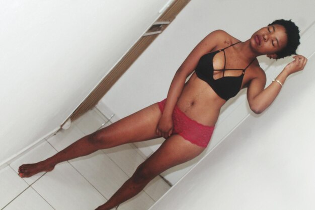 Młoda kobieta w bikini stojąca na ścianie w łazience w domu
