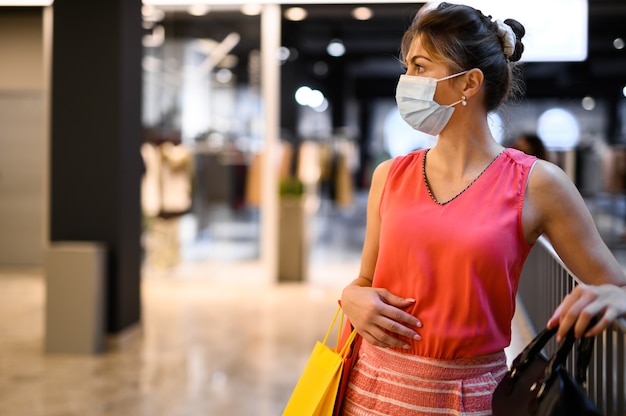 Młoda kobieta w centrum handlowym w masce ochronnej przeciwko pandemii koronawirusa Covid 19