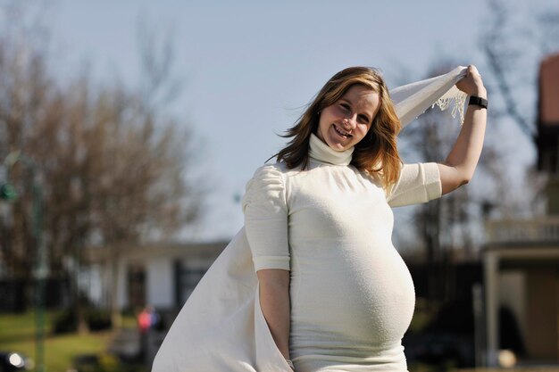 Młoda kobieta w ciąży bawi się na świeżym powietrzu w słoneczny dzień.