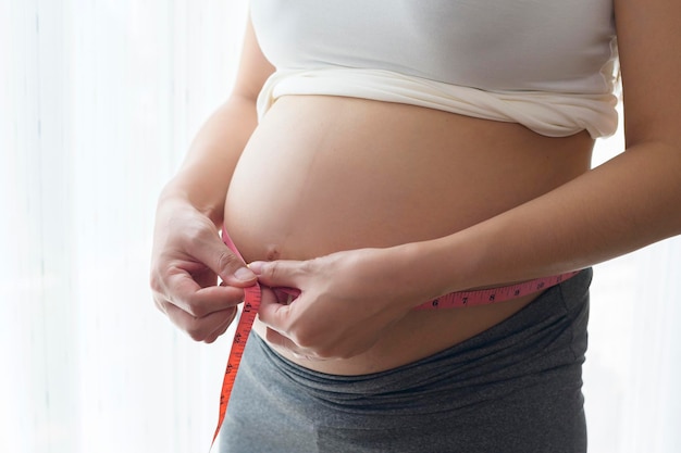 Młoda kobieta w ciąży mierząca centymetr brzucha opieka zdrowotna i opieka nad ciążą