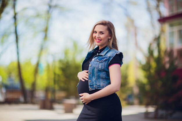Młoda kobieta w ciąży na tle budynku mieszkalnego