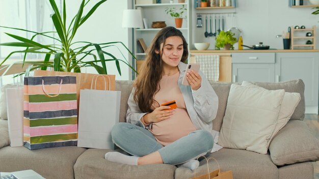 Zdjęcie młoda kobieta w ciąży robi zakupy online za pomocą telefonu i karty kredytowej