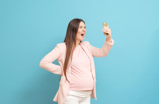Młoda kobieta w ciąży rozmawia przez telefon